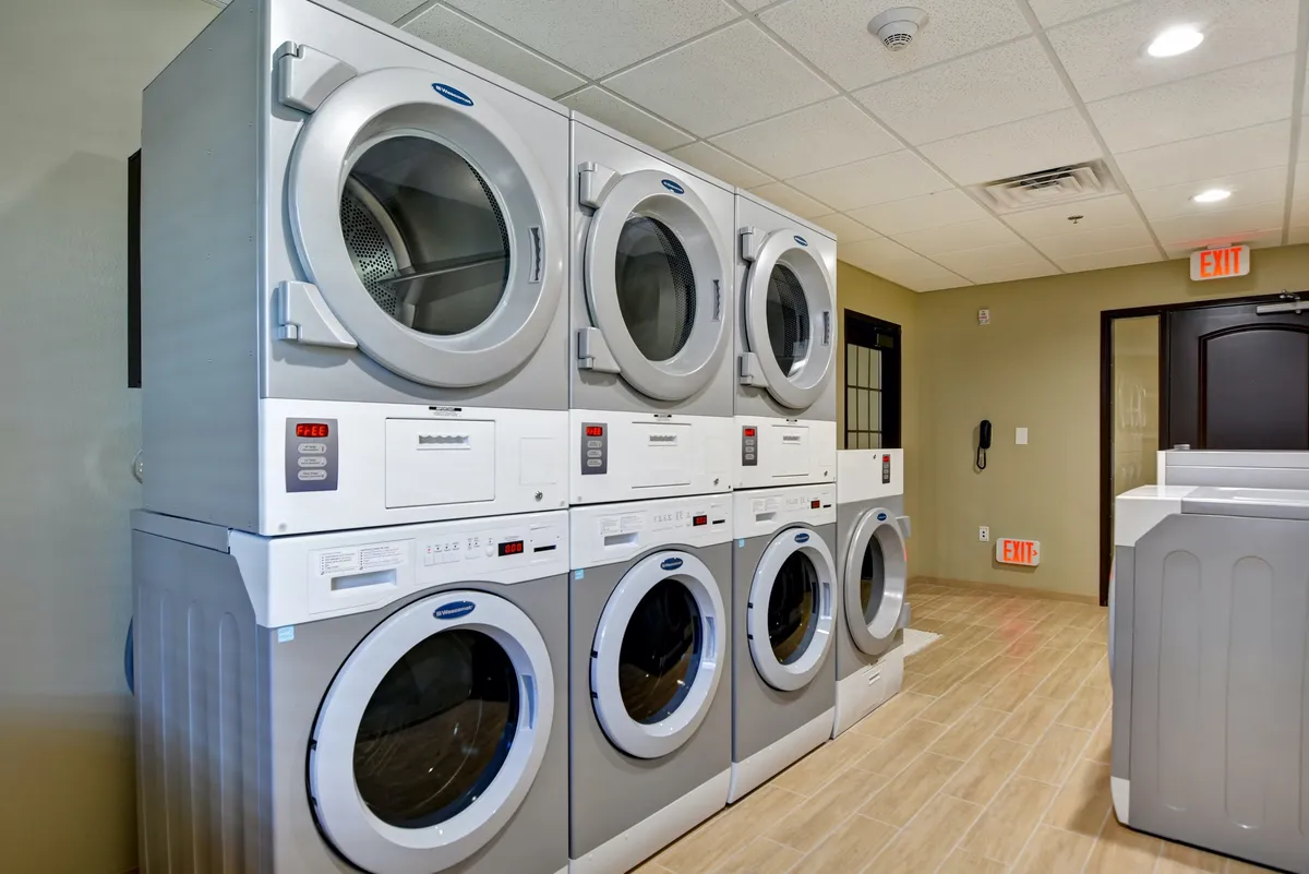 An efficient laundry room with stacked washing machines and dryers. The space is practical, with people doing laundry and socializing as they wait, underscoring the convenience of on-site facilities for longer stays.