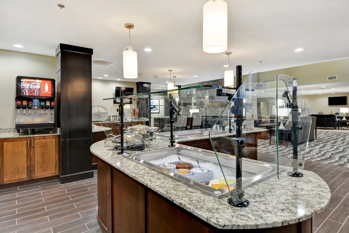 A welcoming breakfast area with a granite countertop, food display, and beverage station. The setup invites guests to enjoy a hearty breakfast or relaxed snack before or after exploring local attractions. The friendly atmosphere hints at community and family appeal.