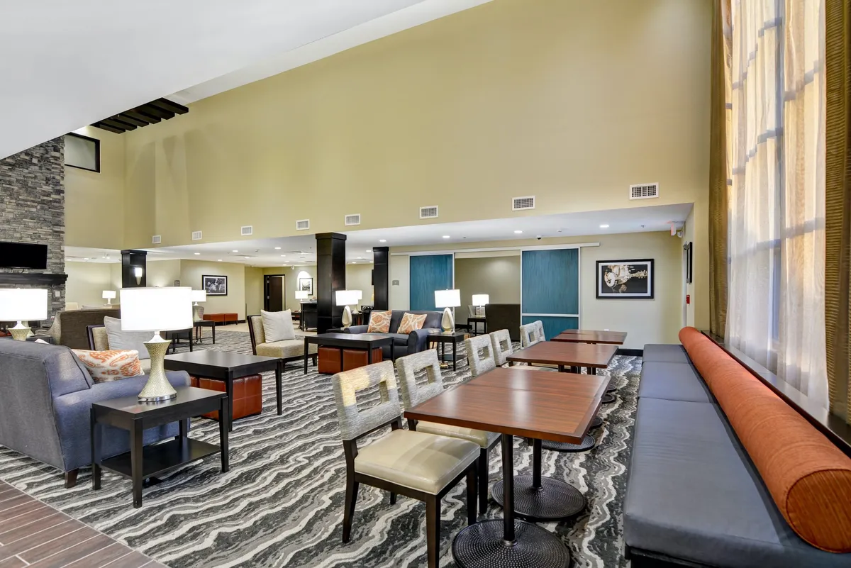A modern communal area is shown with contemporary seating arrangements, stylish lighting, textured flooring, and curated artwork. The space is designed for informal meetings, reading, or simply unwinding, reflecting a welcoming and social environment.